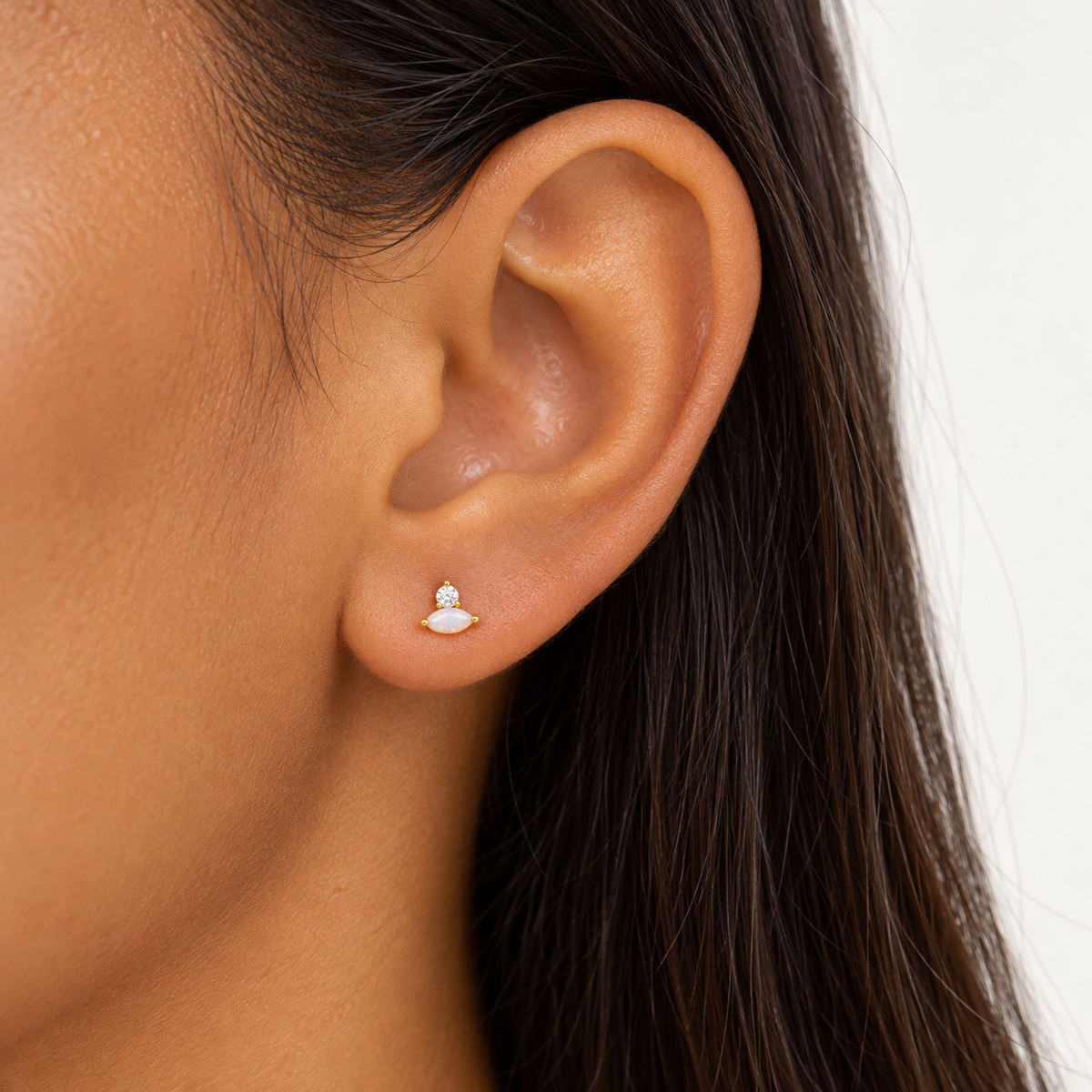 Close-up of a Bajan model wearing the Millie Marquise Stud in gold-plated sterling silver, featuring a white opal marquise stone and sparkling cubic zirconia accent.
