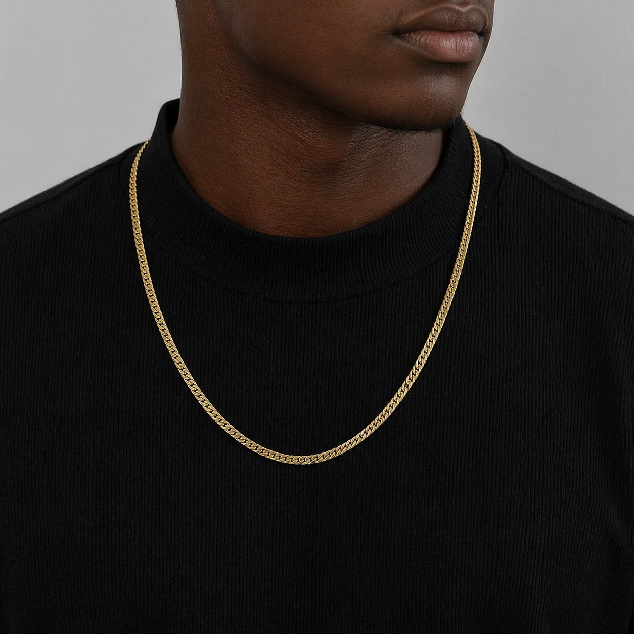 Male wearing a flat linked gold chain against a black shirt