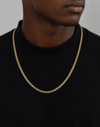 Male wearing a flat linked gold chain against a black shirt