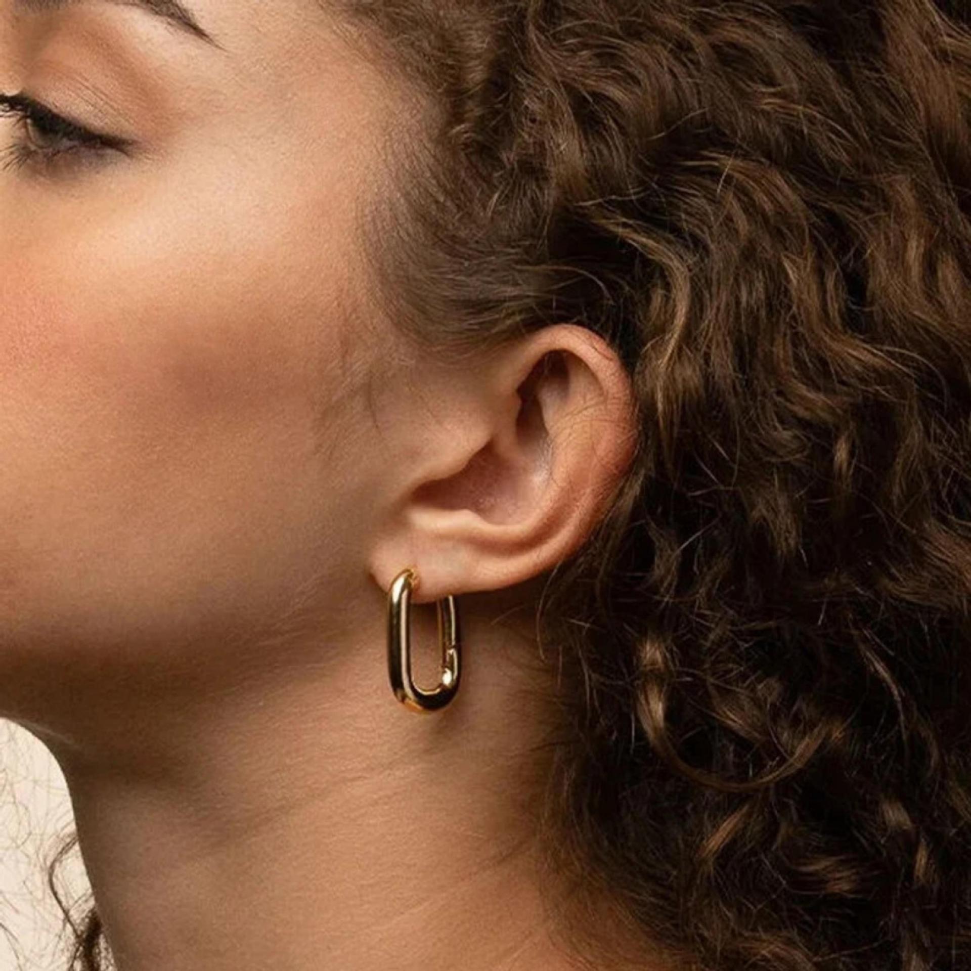 Olivia Huggie Earrings in waterproof gold featuring a modern U shaped hoop design for everyday wear on model