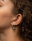 Olivia Huggie Earrings in waterproof gold featuring a modern U shaped hoop design for everyday wear on model