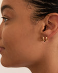  Model wearing two gold-colored CZ huggie earrings in adjacent lobe piercings, side profile view.